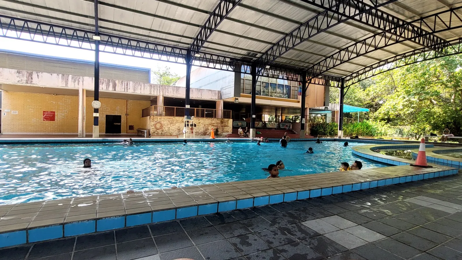 An outdoor swimming pool under a roof