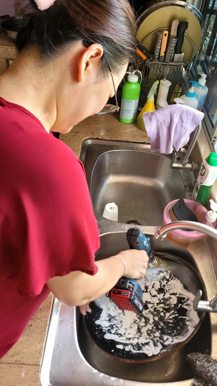My wife scrubbing the pot with a drill brush at the sink